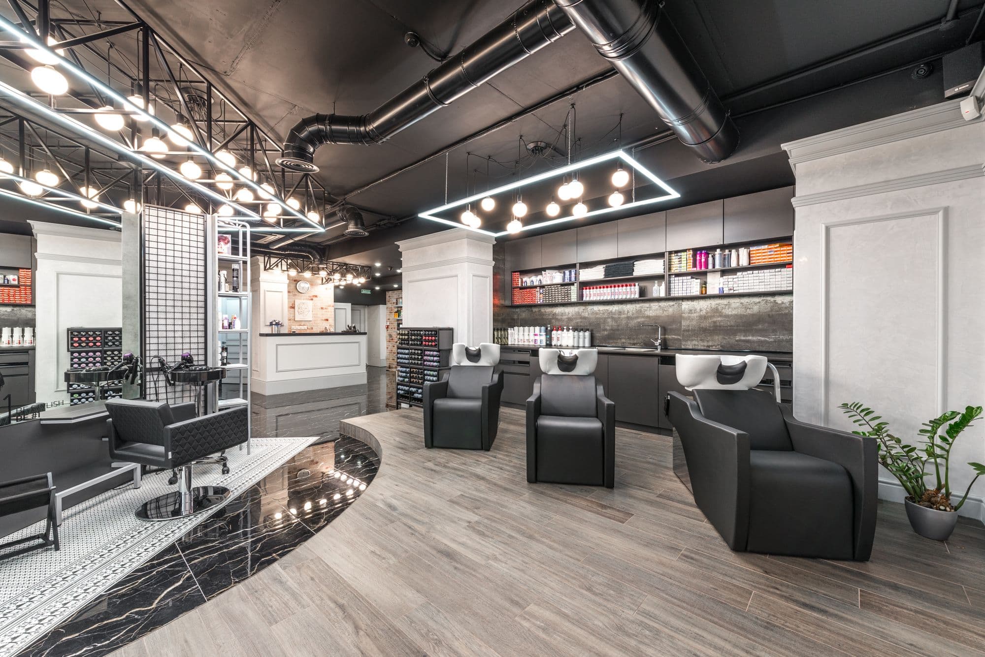La salle du salon Alba : fauteuils de cuir noir, brique et spots